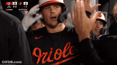 A Baseball Player Wearing A Orioles Jersey High Fives Another Player GIF