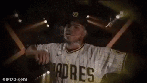 A Baseball Player Wearing A Padres Jersey And Hat Is Standing In Front Of A Stage . GIF