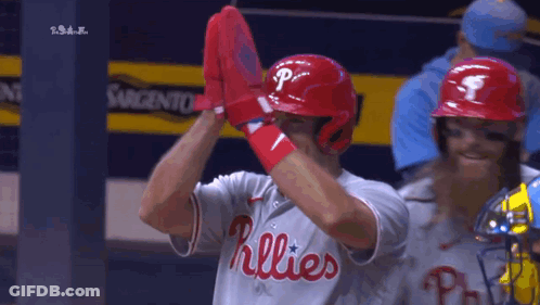 A Baseball Player Wearing A Phillies Jersey Holds Up His Gloves GIF