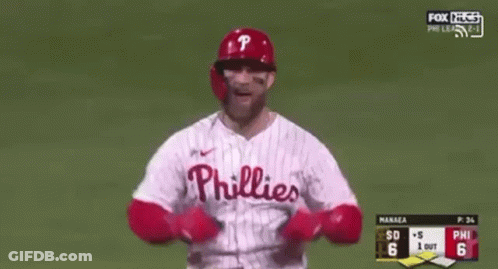 A Baseball Player Wearing A Phillies Jersey Is Standing On A Baseball Field With His Arms In The Air . GIF