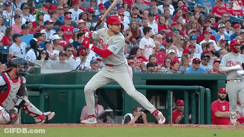 A Baseball Player Wearing A Phillies Jersey Is Swinging At A Pitch GIF