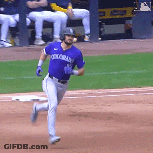 A Baseball Player Wearing A Purple Colorado Jersey Is Running To First Base . GIF