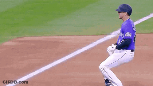 A Baseball Player Wearing A Purple Jersey With The Number 24 On It Is Running Towards The Base . GIF