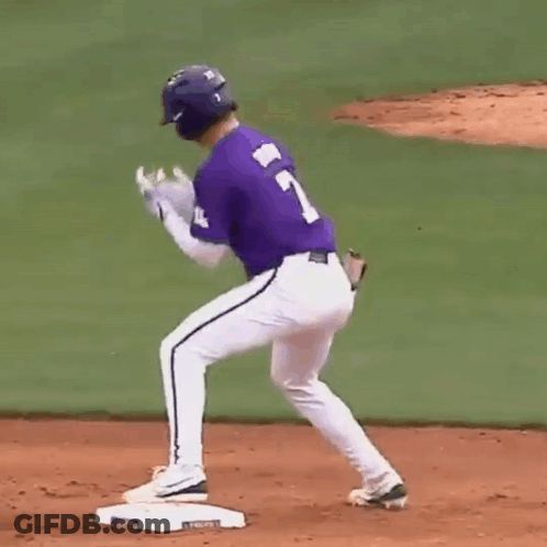 A Baseball Player Wearing A Purple Jersey With The Number 7 On It Is Standing On The Base . GIF