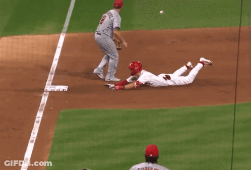 A Baseball Player Wearing A Red Helmet Is Running Towards Home Plate GIF