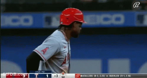 A Baseball Player Wearing A Red Helmet Stands In Front Of A Scoreboard That Says ' Lyles Pai ' On It GIF