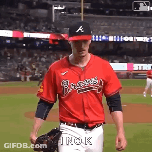 A Baseball Player Wearing A Red Jersey And A Black Hat Is Walking On The Field . GIF