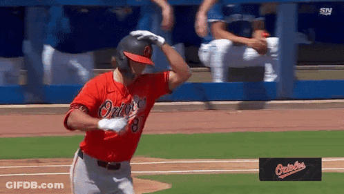 A Baseball Player Wearing A Red Orioles Jersey Is Standing On The Field GIF