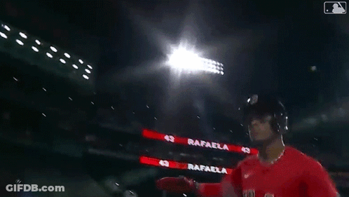 A Baseball Player Wearing A Red Sox Jersey Is Standing Next To Another Player In A Dark Stadium . GIF