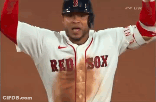 A Baseball Player Wearing A Red Sox Jersey Is Standing On A Field With His Arms In The Air . GIF