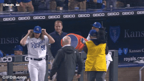 A Baseball Player Wearing A Royals Uniform Is Being Escorted By A Man In A Yellow Jacket GIF