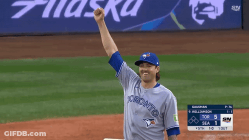 A Baseball Player Wearing A Toronto Jersey Holds His Fist Up In The Air GIF