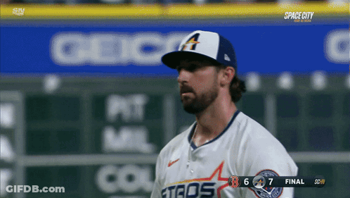 A Baseball Player Wearing A White Astros Jersey Stands In Front Of A Scoreboard GIF