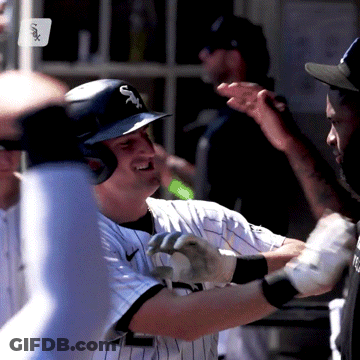 A Baseball Player Wearing A White Sox Helmet Is Being High Fived By His Teammates GIF