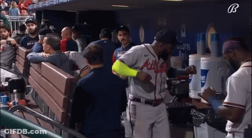 A Baseball Player Wearing An Atlanta Braves Jersey Stands In A Dugout GIF