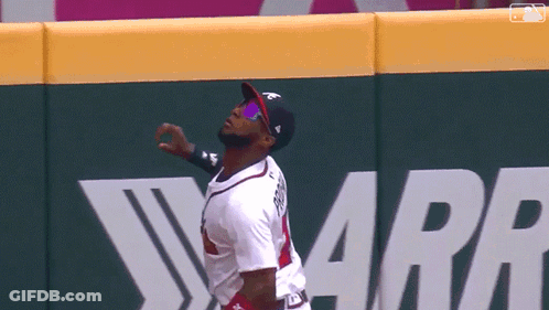 A Baseball Player Wearing Sunglasses And A Hat Stands In Front Of A Wall That Says Warr GIF