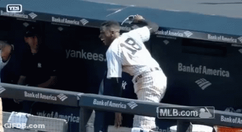 A Baseball Player With The Number 18 On His Back Stands In A Dugout GIF