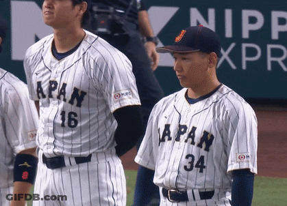 A Baseball Player With The Number 34 On His Jersey Stands Next To Another Player GIF