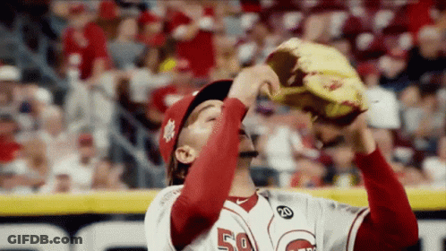 A Baseball Player With The Number 50 On His Jersey Is Holding His Glove Up In The Air . GIF