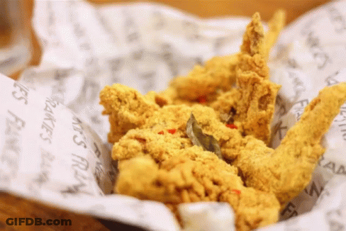 A Basket Of Fried Chicken Is Sitting On A Piece Of Paper That Says ' Fries ' On It GIF