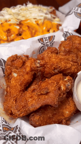 A Basket Of Fried Chicken Wings Sits On A Table GIF