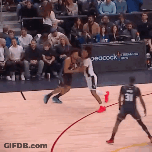 A Basketball Game Is Being Played In Front Of A Peacock Sign . GIF