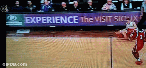 A Basketball Game Is Being Played In Front Of A Sign That Says " Experience The Visit Sioux " GIF