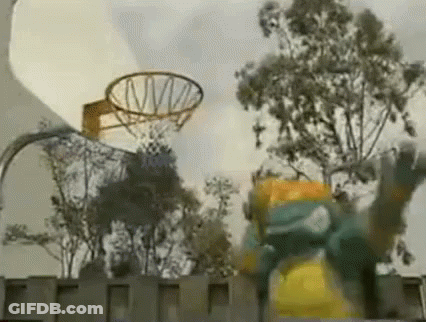 A Basketball Hoop Is Surrounded By Trees And A Person Is Jumping In The Air . GIF