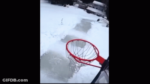 A Basketball Is Going Through A Hoop In The Snow With A House In The Background GIF