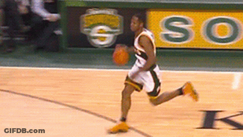 A Basketball Player Dribbles A Ball On A Court With A So Sign Behind Him GIF