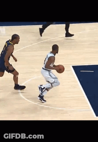 A Basketball Player Dribbles A Ball While Another Player Tries To Stop Him GIF