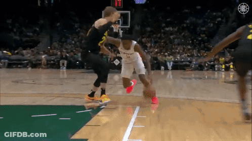 A Basketball Player Dribbles The Ball While Another Player Tries To Stop Him . GIF