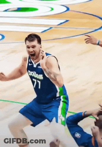 A Basketball Player In A Blue And Green Uniform Is Jumping In The Air On A Court . GIF