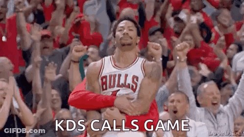 A Basketball Player In A Bulls Jersey Is Standing In Front Of A Crowd With His Fist In The Air . GIF