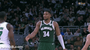 A Basketball Player In A Milwaukee Jersey Is Shaking Hands With Another Player . GIF