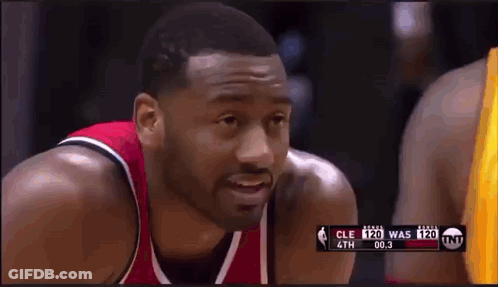 A Basketball Player In A Red And Black Jersey Is Looking At The Camera During A Game GIF
