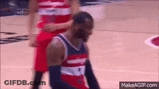 A Basketball Player In A Red White And Blue Jersey Is Kneeling Down On The Court GIF