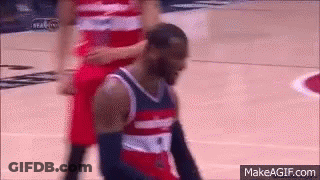 A Basketball Player In A Red , White And Blue Uniform Is Kneeling Down On The Court . GIF
