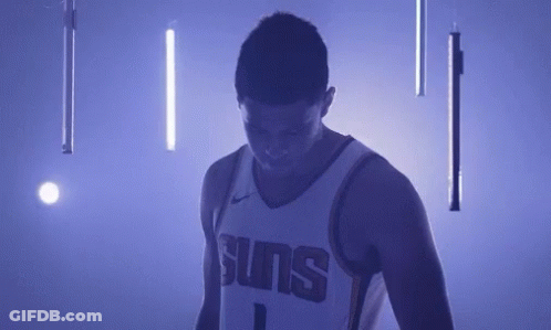 A Basketball Player In A Suns Jersey Is Standing In A Dark Room With Purple Lights . GIF