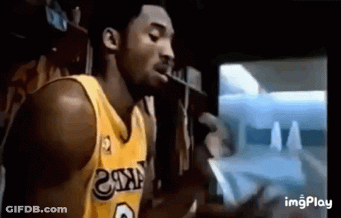 A Basketball Player In A Yellow Jersey Is Smoking A Cigarette In Front Of A Tv . GIF