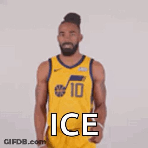 A Basketball Player In A Yellow Jersey Is Standing In Front Of A White Wall . GIF