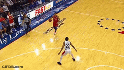 A Basketball Player Is Dribbling The Ball On A Court While Another Player Tries To Block Him . GIF