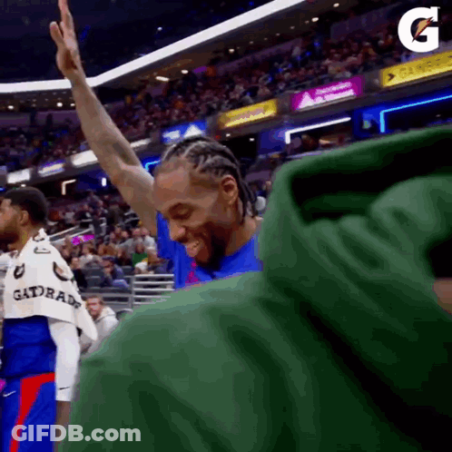 A Basketball Player Is Giving A High Five To The Crowd While Wearing A Green Gatorade Shirt . GIF