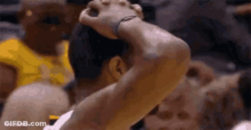 A Basketball Player Is Holding His Head In His Hands While Playing A Game . GIF