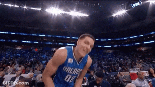 A Basketball Player Is Jumping In The Air In Front Of A Crowd . GIF