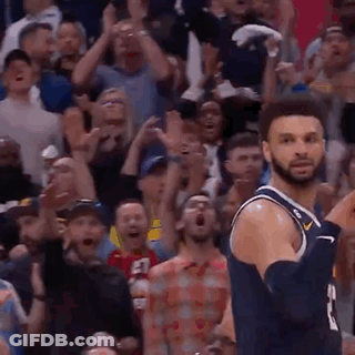 A Basketball Player Is Jumping In The Air In Front Of A Crowd Of People . GIF