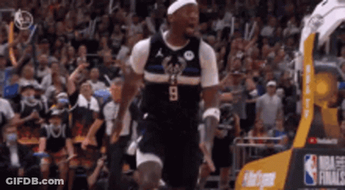 A Basketball Player Is Jumping In The Air In Front Of A Crowd Of People . GIF