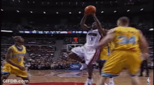 A Basketball Player Is Jumping In The Air To Catch A Basketball While Playing Basketball . GIF