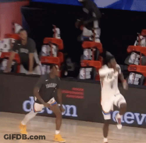 A Basketball Player Is Jumping In The Air While Another Player Looks On During A Game GIF