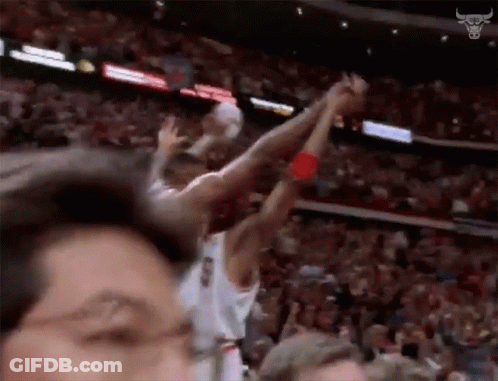 A Basketball Player Is Jumping In The Air With His Arms In The Air While A Crowd Watches . GIF